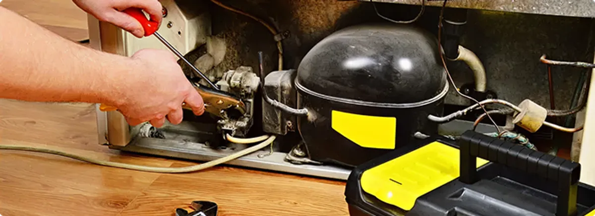 Refrigerator repair technician fixing the compressor and wiring in Carmichael, CA