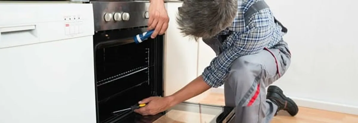Oven repair technician inspecting and servicing an electric oven in Sacramento, CA